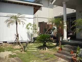 フェニックス・ロベレニー、ソテツ、シマトネリコ、ココスヤシなどを植栽し、アプローチは古木の枕木を使用しています。