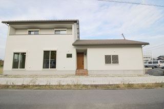 白壁とダークブランの屋根。木目調の玄関ドアをアクセントに、ツートンカラーで統一したシンプルな北欧風の家です。