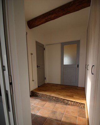 玄関/床はテラコッタタイル、土間と框の段差にはモザイクタイル、天井には古材の丸太をアクセントに用いています。右側は大容量のシューズクローゼットがあります。