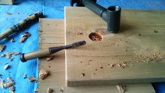 棚板にパイプを通すための穴を掘るために、丸のみでくり抜き中。